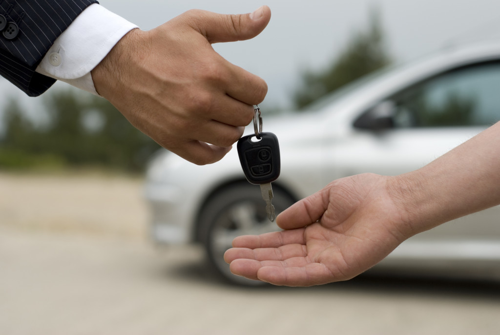 car salesman handing the car key to a customer