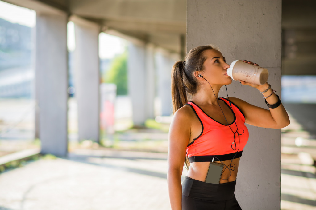 woman drinking water after doing workout