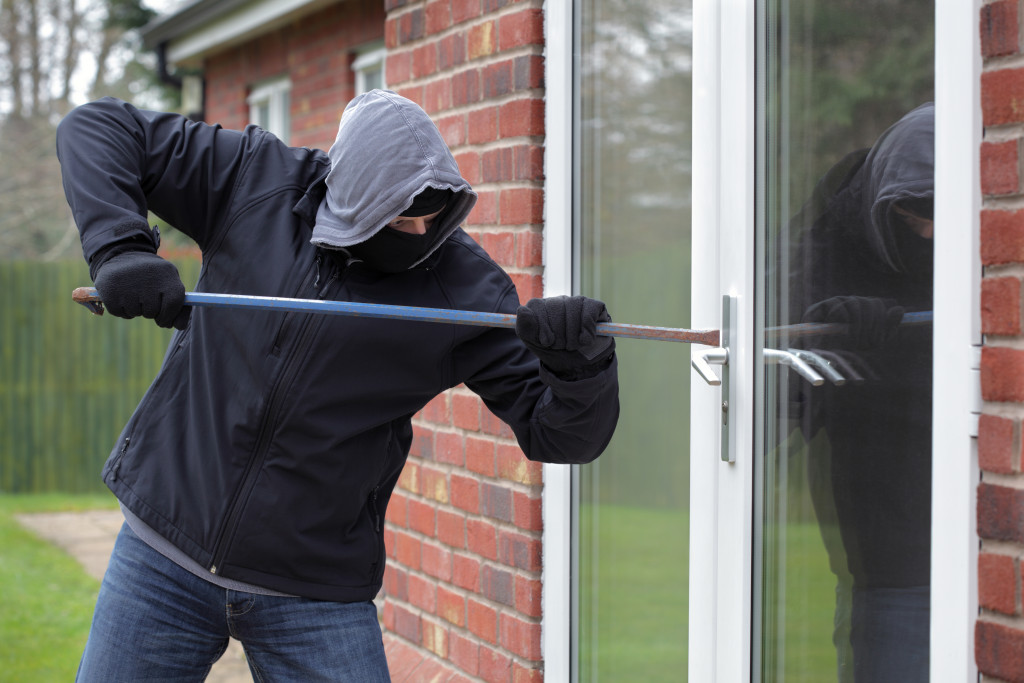 A burglar using a crowbar to force open a home glass door