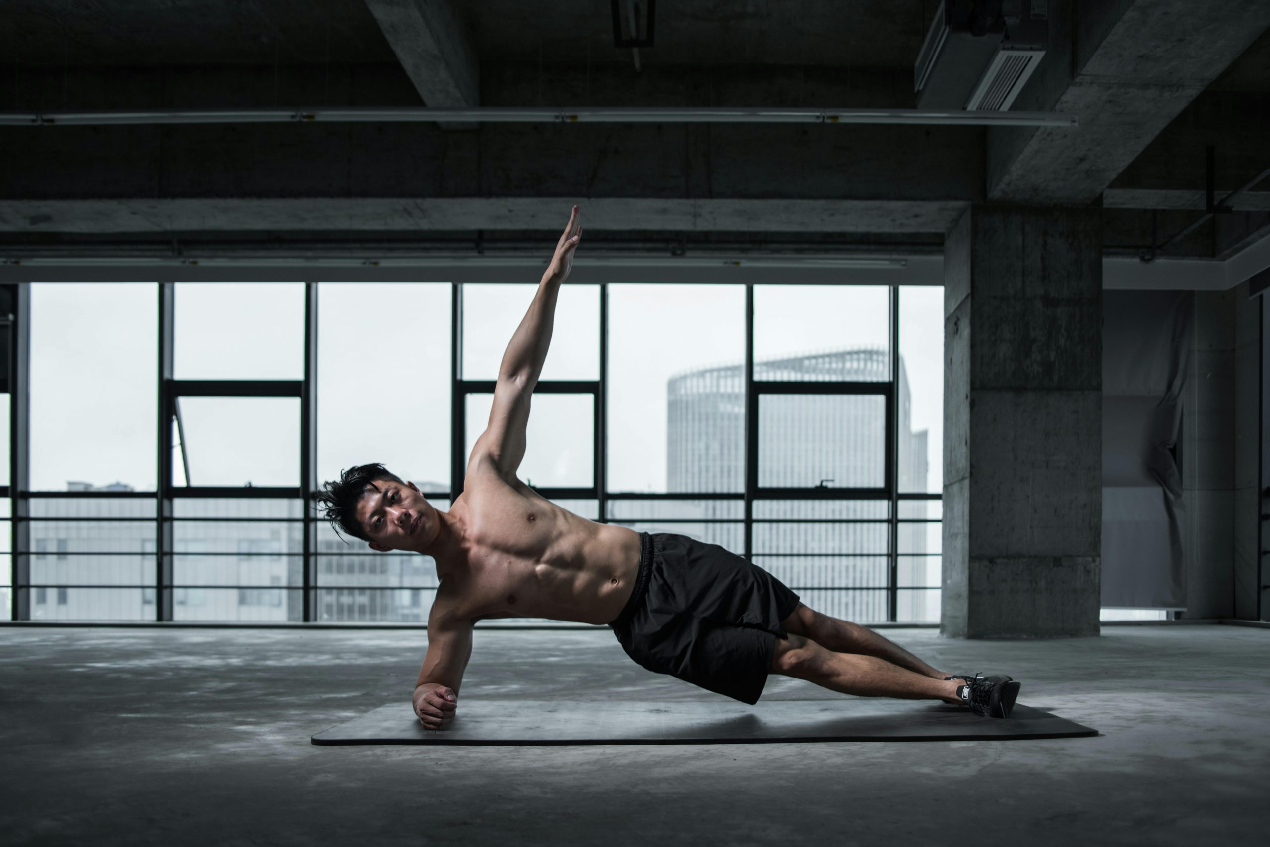 fit man performing a side plank while raising one arm