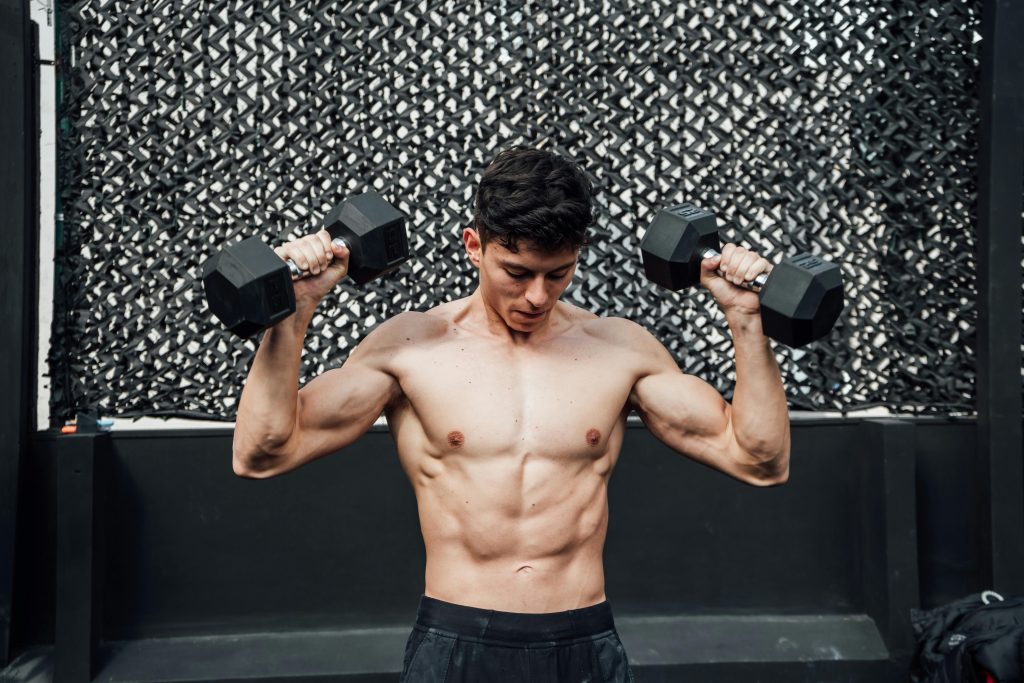 muscular man lifting two dumbbells during a workout