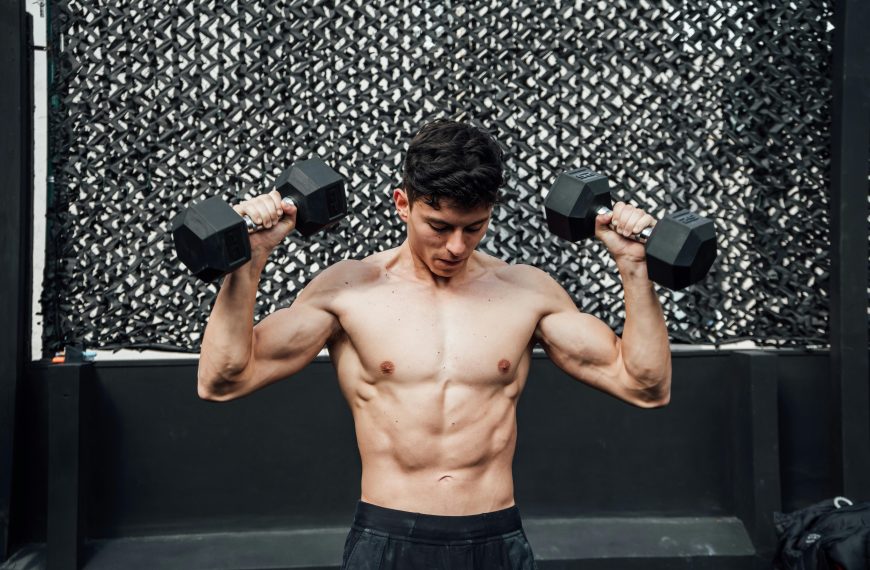 muscular man lifting two dumbbells during a workout